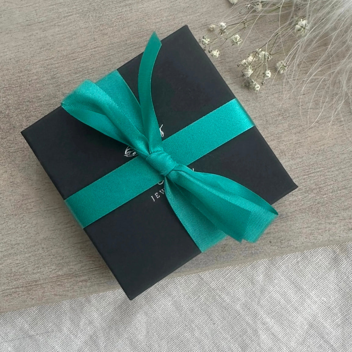 a black gift box with a green ribbon